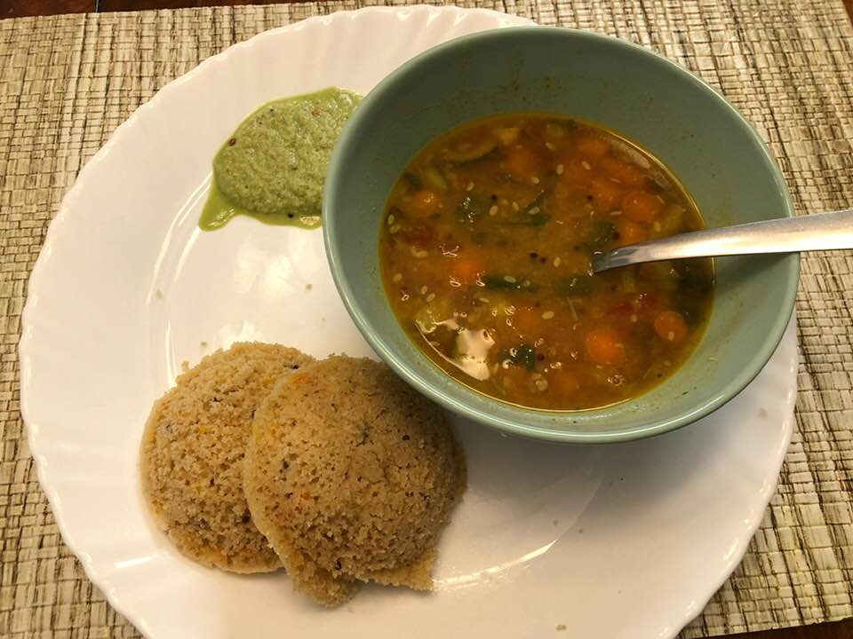 A plate with 2 Gluten Free idlis, a vegetable indian curry, and green mint and coconut sauce