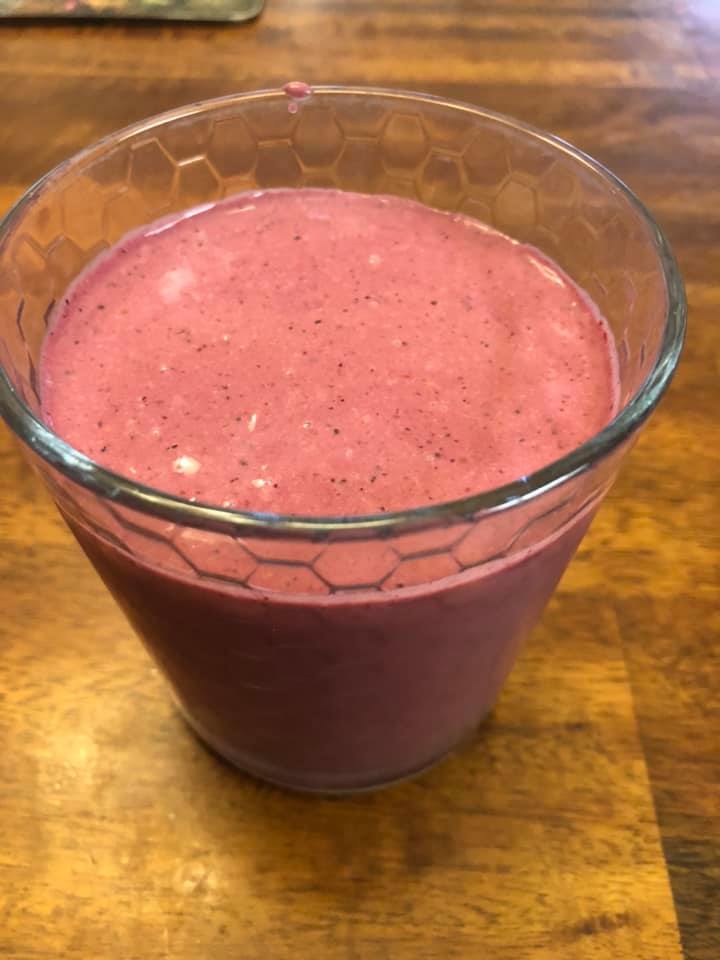 A glass of pink smoothie filled to the brim